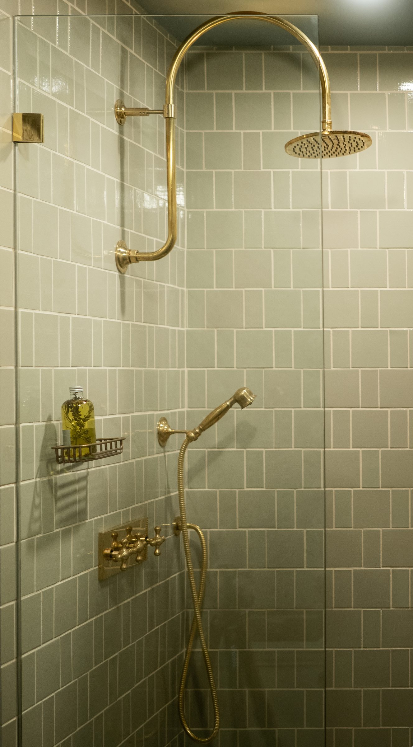 A shower with a brass rain head against tile