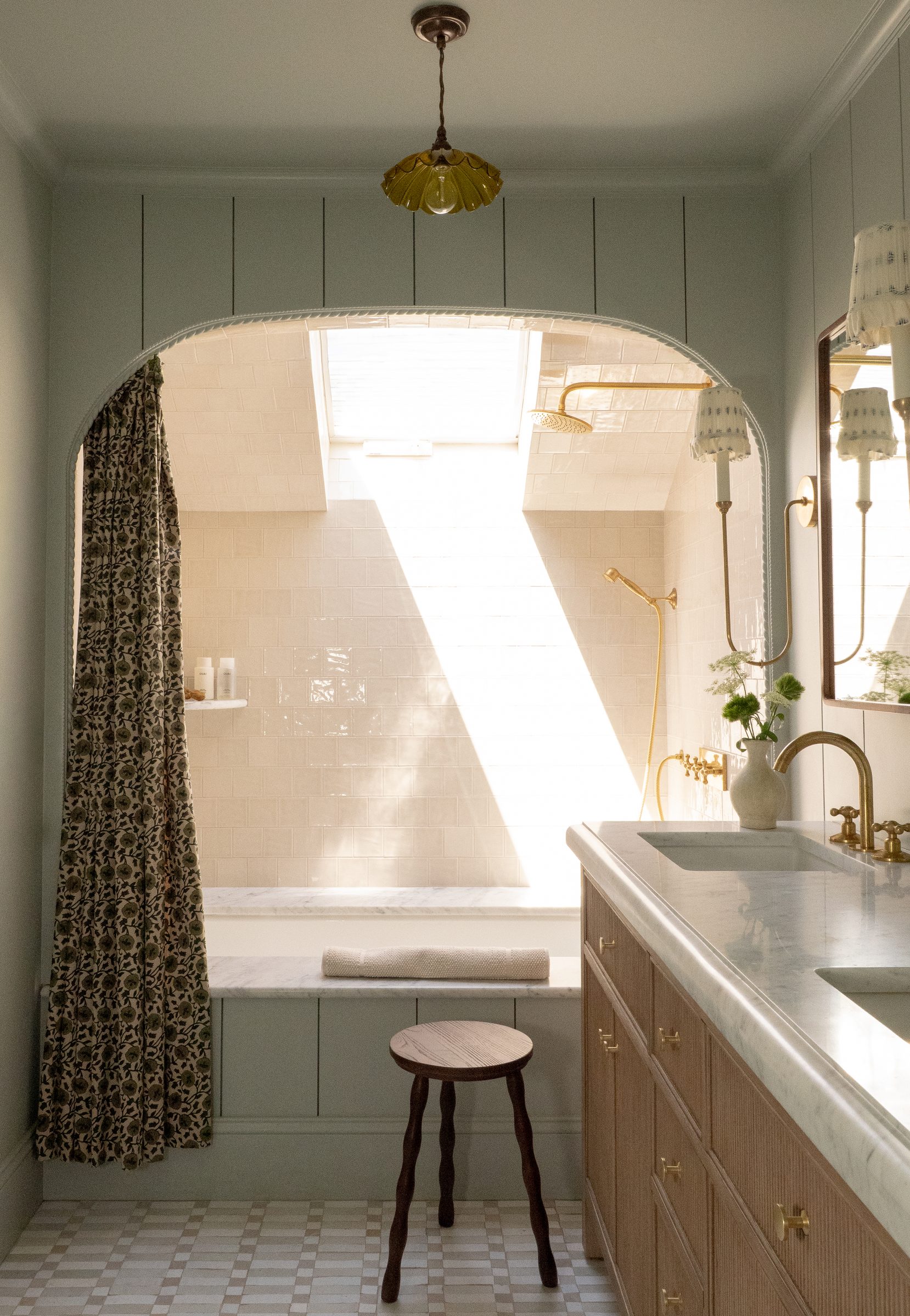 The primary bath's arched tub nook with a skylight and floral curtain