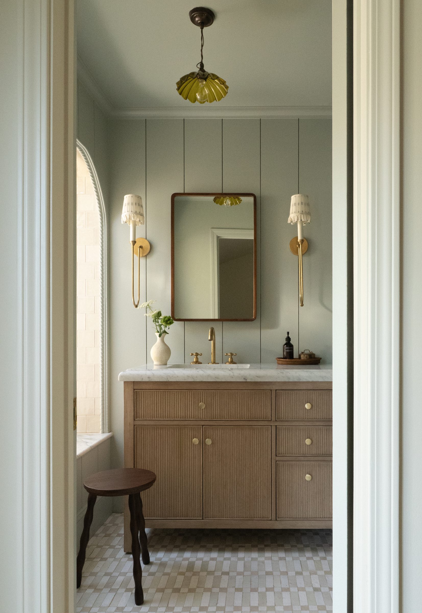 The primary bath vanity with a mirror and brass sconces