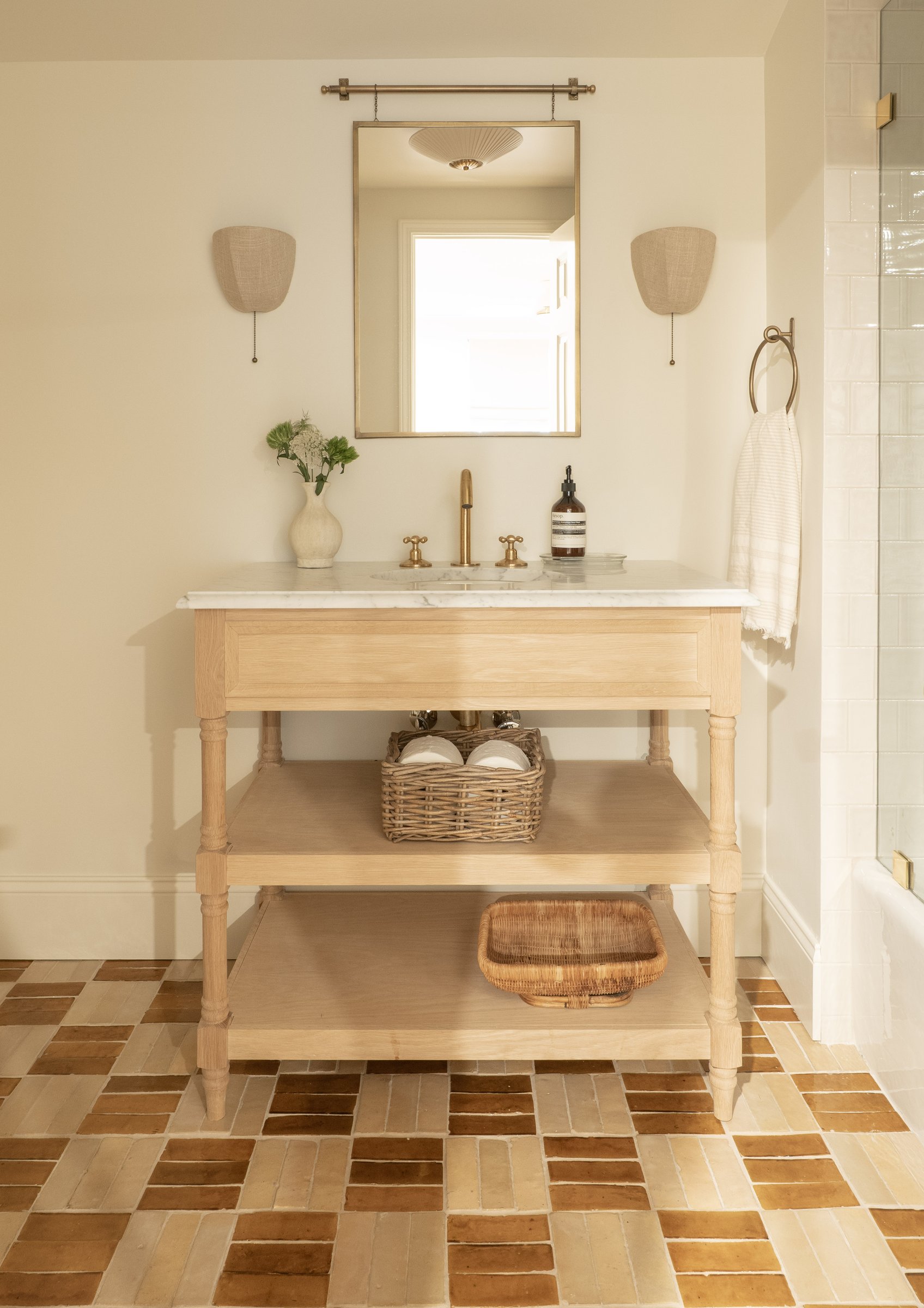 A light oak vanity table with a marble top and terracotta tile floor