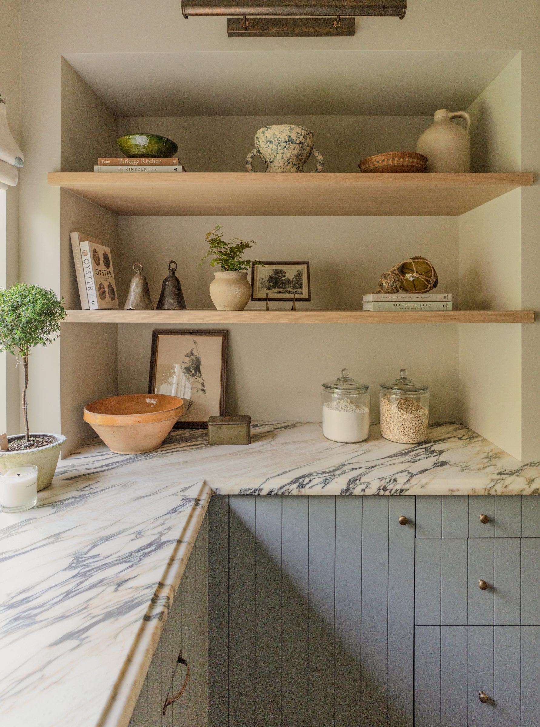 Open kitchen shelving styled with ceramics, books, and a terracotta bowl