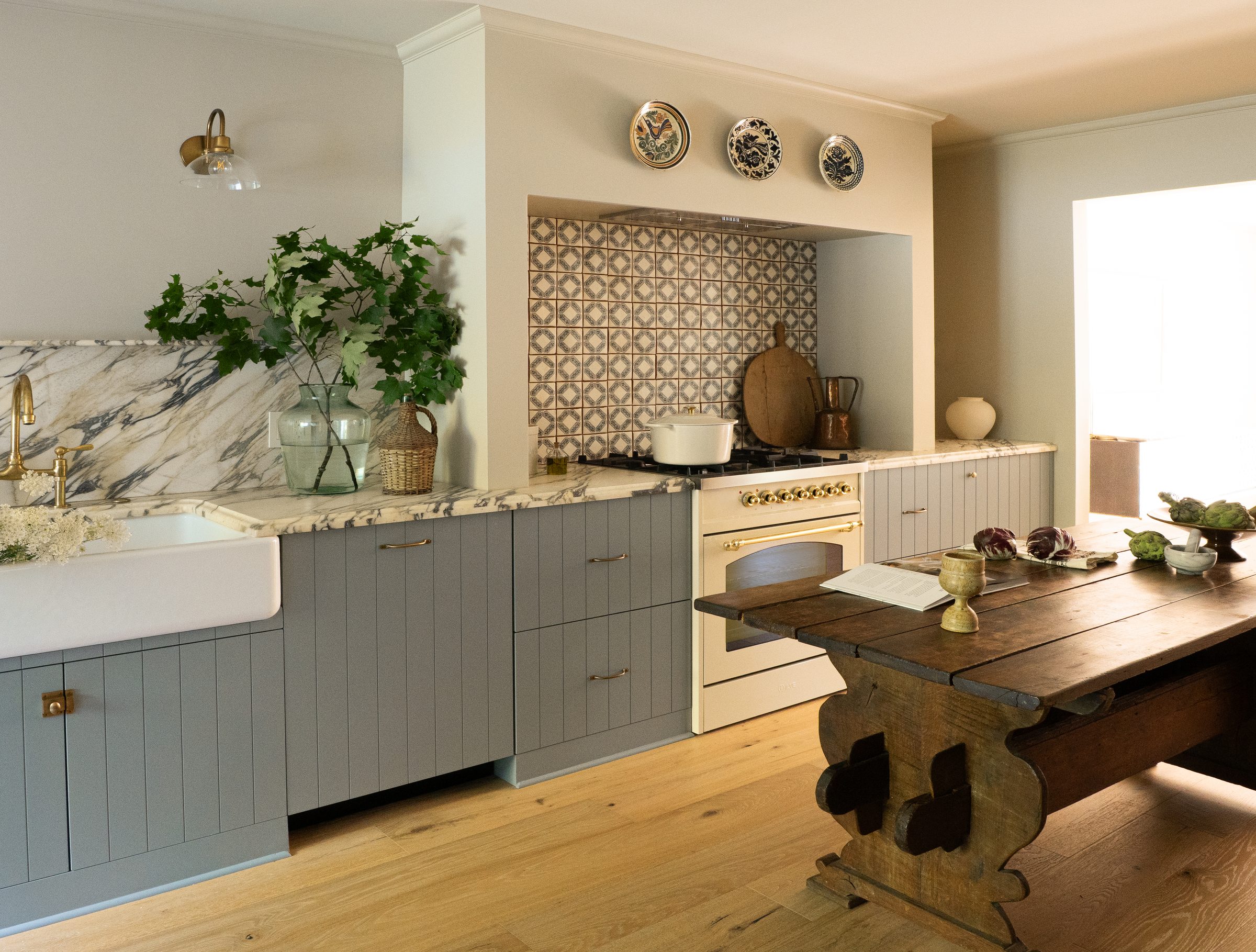 A wide view of the kitchen with the farmhouse sink, marble backsplash, and dining table beyond